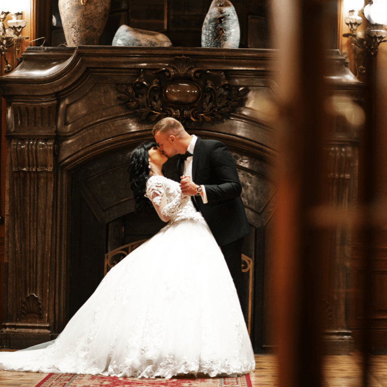 groom kissing bride in front of a fireplace