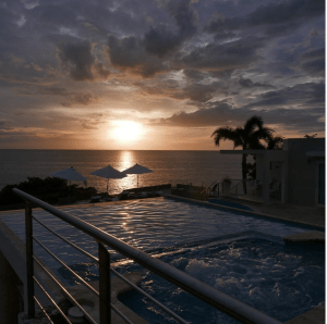 Infiniti pool with ocean in the background and two palm trees