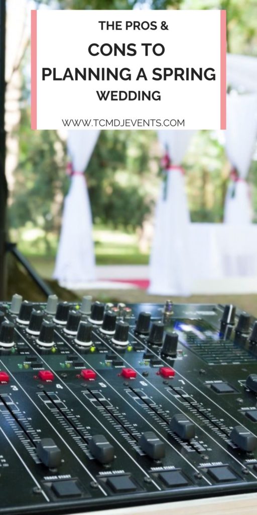DJ mixer outside with white wedding alter in the distance