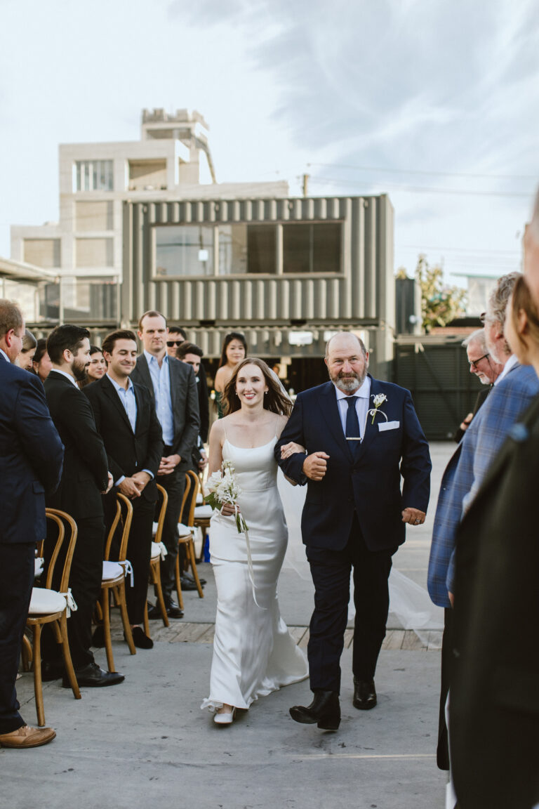 jessica and her father walk down the isle with bushwick in the background