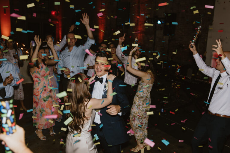 wedding party dancing to the music while confetti falls around them